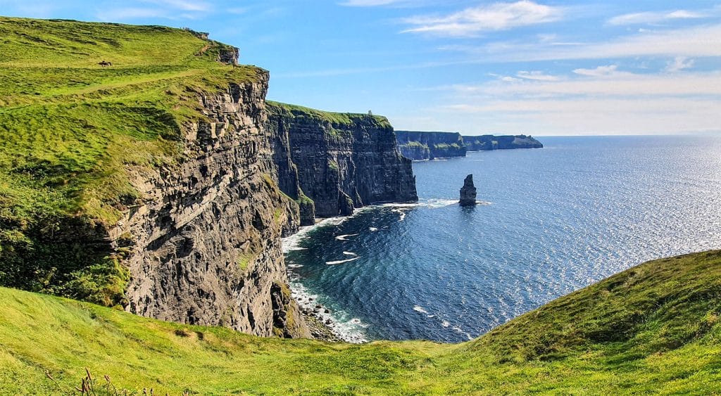 Green Ireland fields and ocean cliffs.