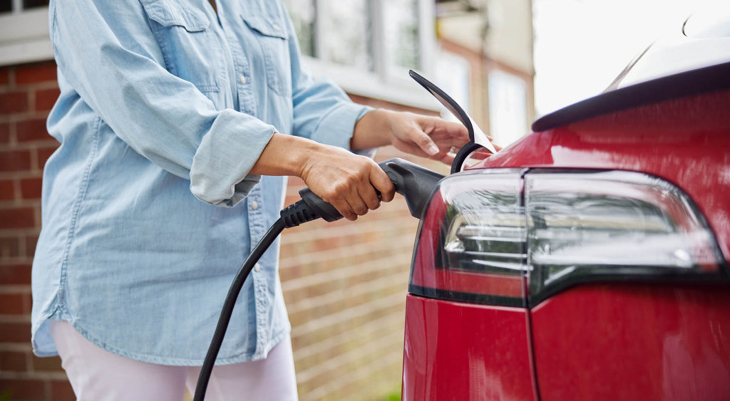 A person charging their electric vehicle in the driveway.