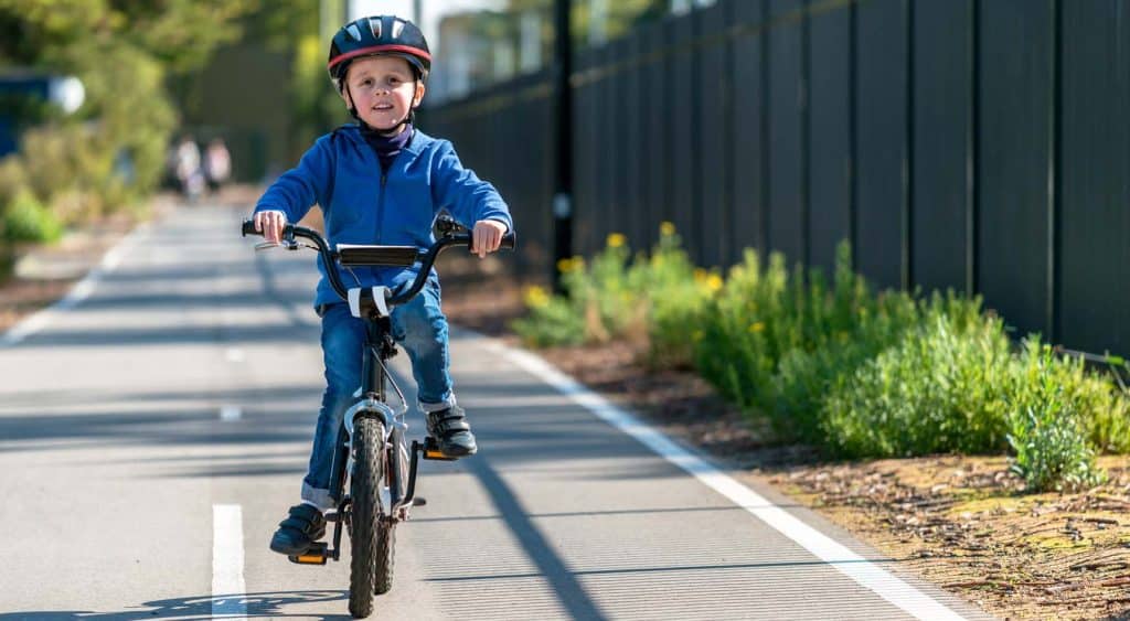A kid riding a bicycle along a bike track.