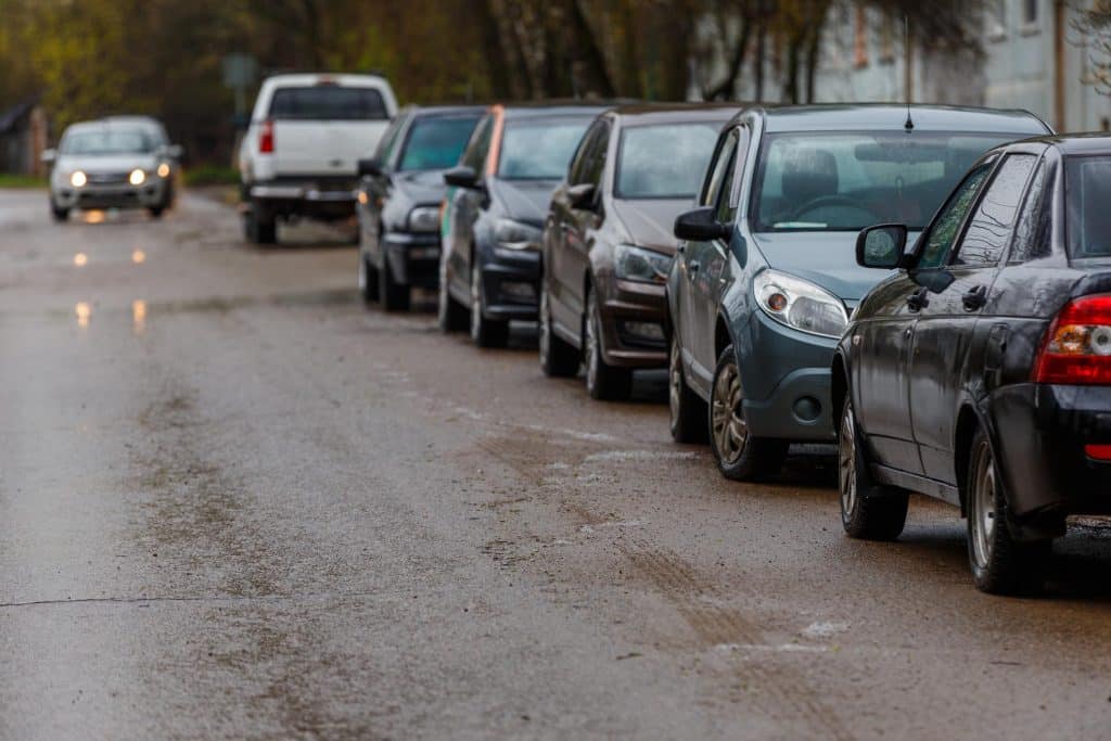Cars parallel parked in both directions on the road.