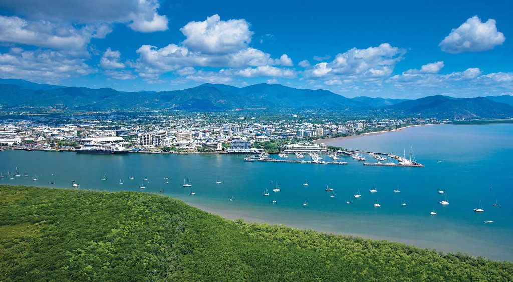The Cairns landscape with greenery in the foreground and mountains in the background.