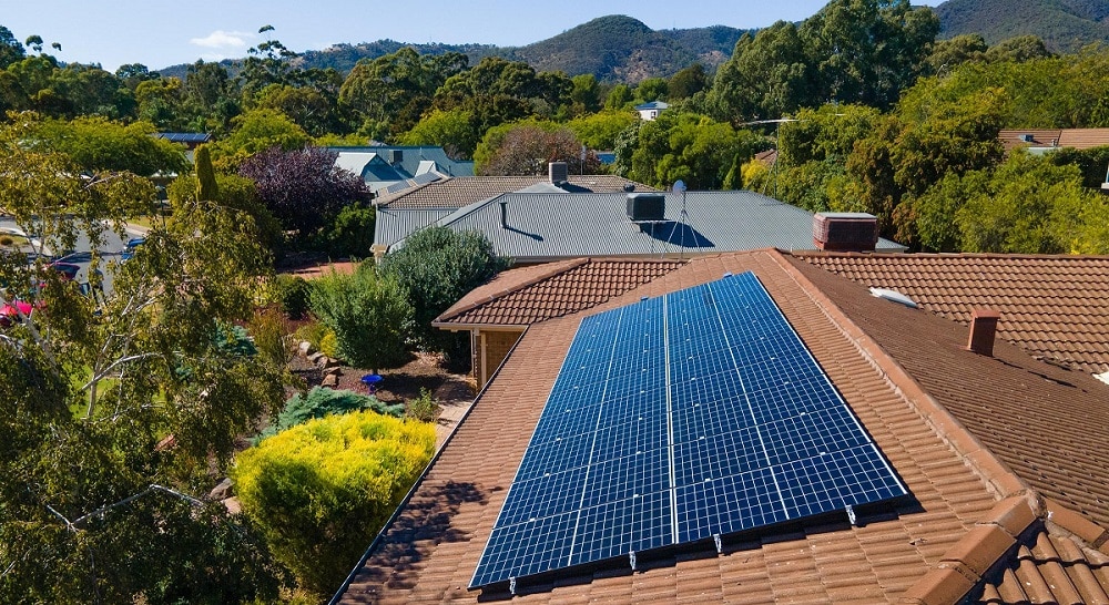 Solar panels on a roof with hills in background.