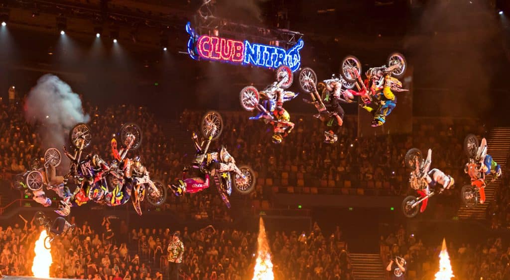 Nitro Circus motorcyclists flying upside before a big crowd.