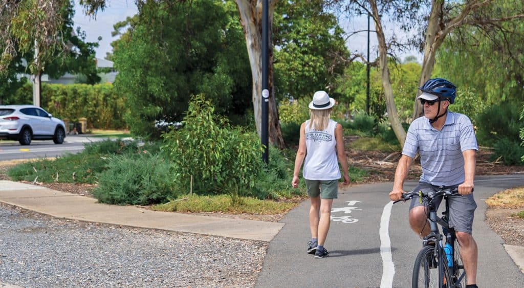 Cyclist and pedestrian on a shared path near a busy road.