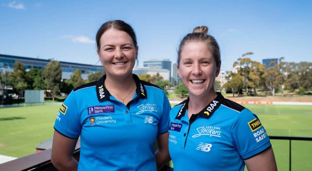 Jemma Barsby and Ellie Johnston pose in front of the camera in front of Karen Rolton Oval.