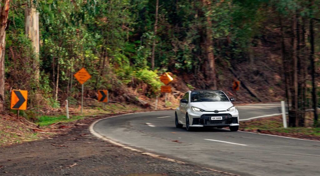 The Toyota GR Yaris on a windy road passing forest.