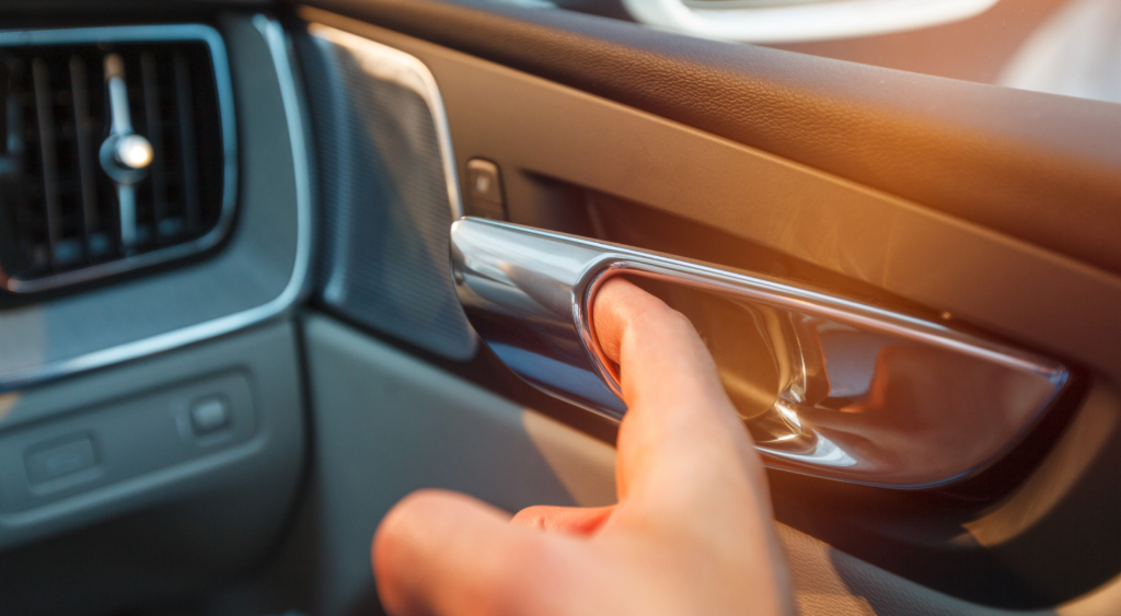A hand is seen grasping the door handle of a car, ready to pull it open.