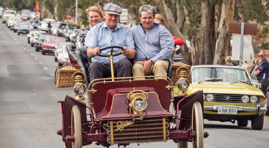 Four people in a vintage Cadillac driving in McLaren Vale