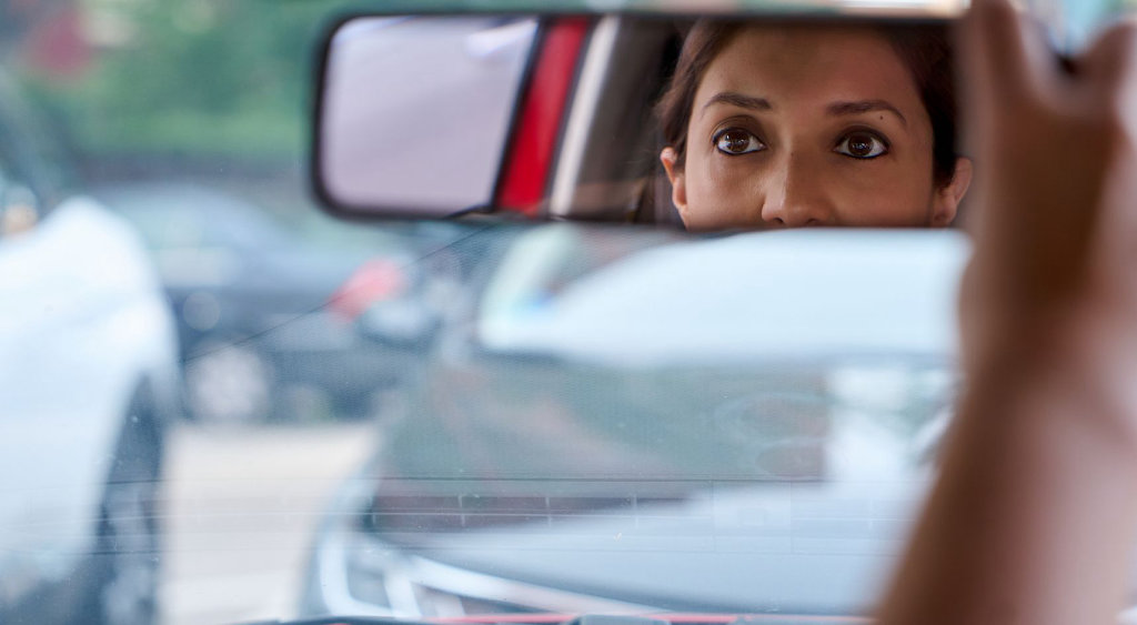 Woman's face in rear-view mirror.