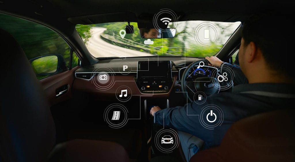 A person driving a car with icons displayed for all the different tech in the car.