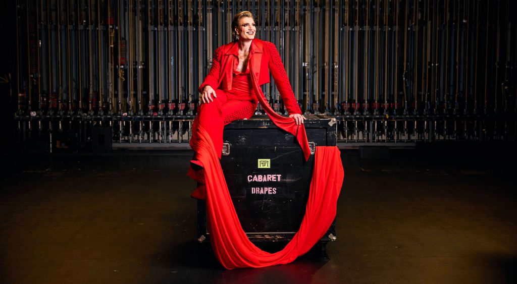 Reuben Kaye wearing red draped backstage.
