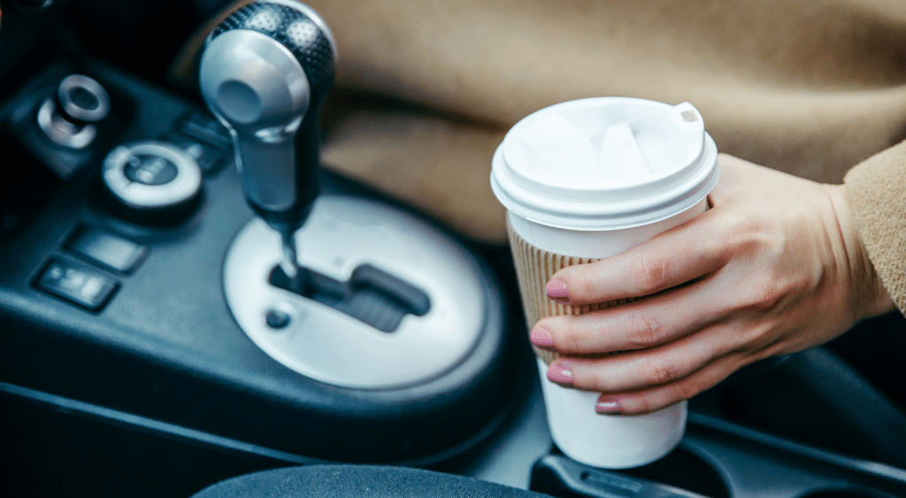 Driver picking up coffee in car.