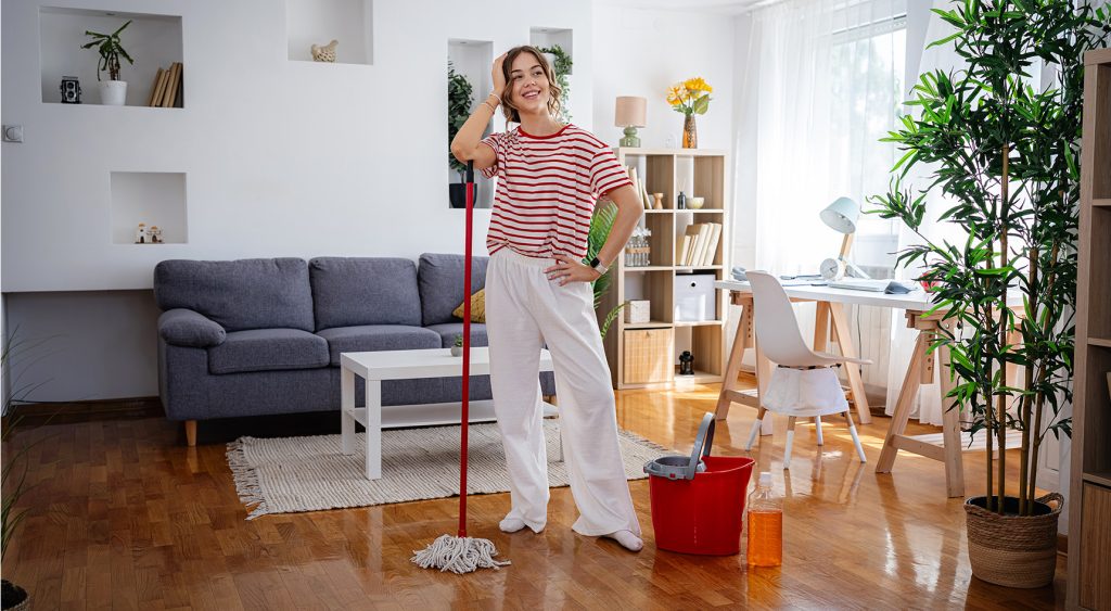 A woman standing and admiring her work after cleaning the house