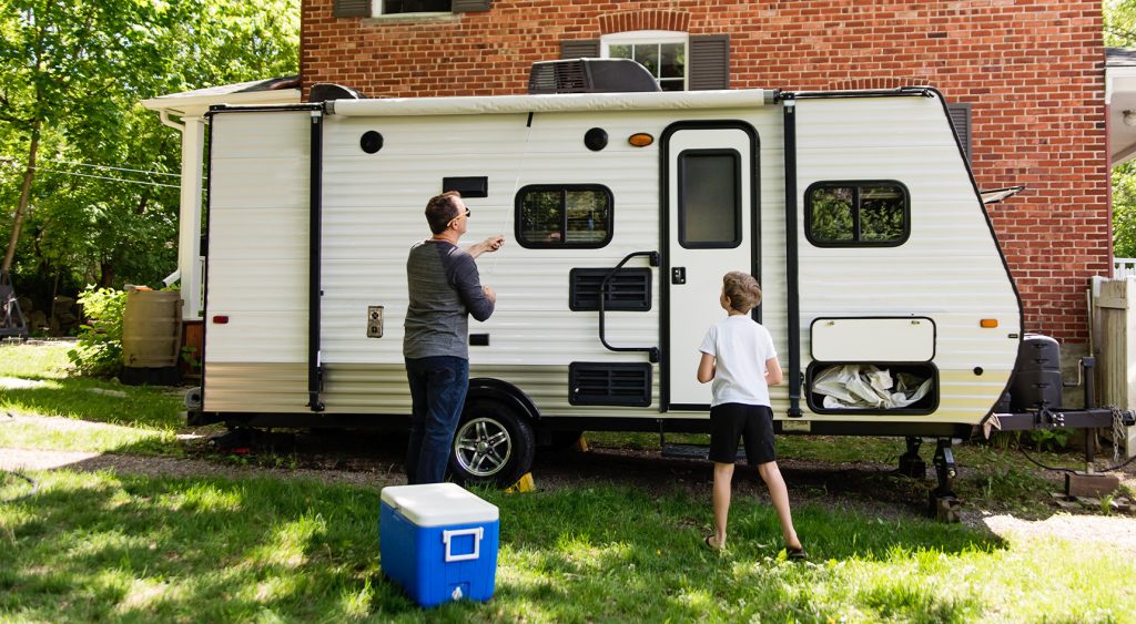 A father and son preparing their caravan for camping in a driveway
