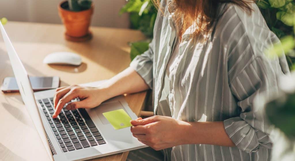 Person holding credit card while looking on their laptop